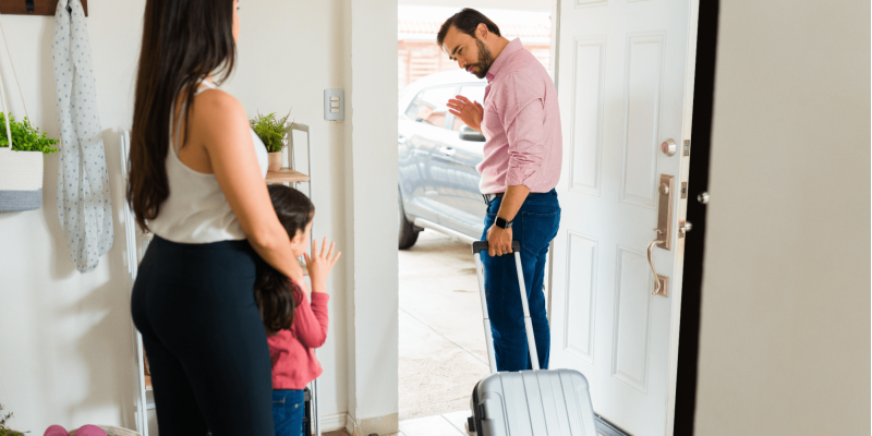 a man walking out the door, a woman and a child are standing by and watching him leave