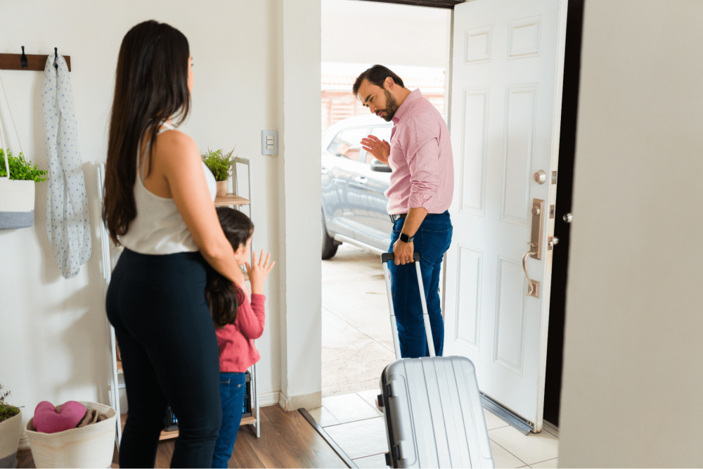 a man walking out the door, a woman and a child are standing by and watching him leave