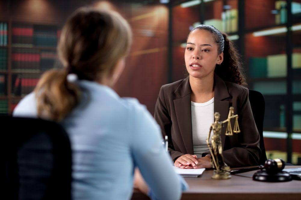 a woman sitting at a desk talking to another woman